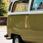 Close-up view of a vintage green camper van parked outdoors on a sunny day, capturing a retro vibe.